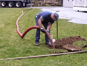 Septic pumping technician servicing a residential septic tank with a vacuum hose in Charleston, SC